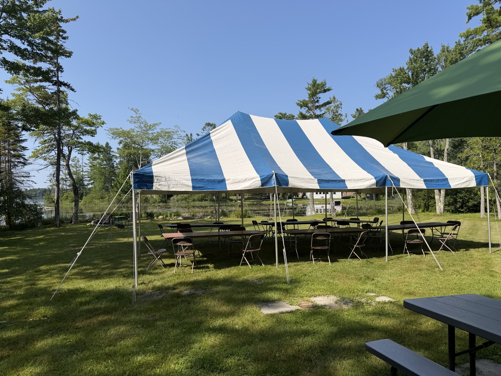 Blue and white striped canopy tent set up with tables and chairs