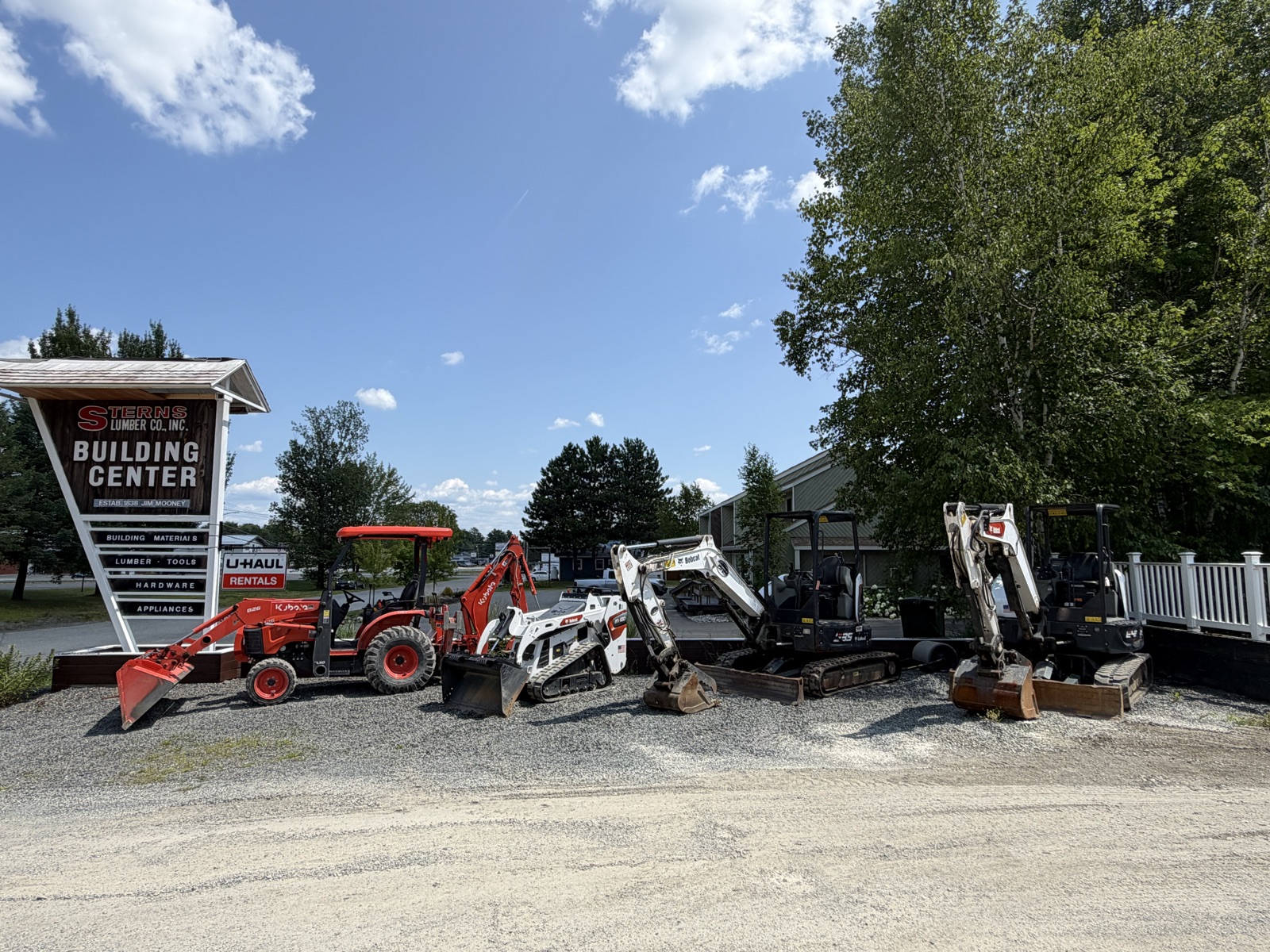 Rental tractor and mini excavators lined up in front of the Building Center sign